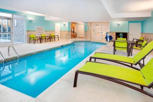 uma piscina com cadeiras e mesas num edifício em SpringHill Suites by Marriott Hampton Portsmouth em Hampton