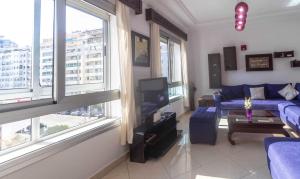 a living room with a blue couch and windows at Appartement Haut Standing Central Corniche in Tangier
