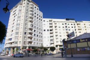 a large white building with cars parked in front of it at Appartement Haut Standing Central Corniche in Tangier