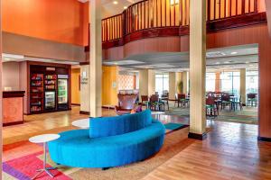 a lobby with a blue couch and tables and chairs at Fairfield Inn & Suites by Marriott Anniston Oxford in Oxford