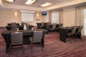 a conference room with tables and chairs and a screen at Courtyard by Marriott Dulles Airport Chantilly in Chantilly