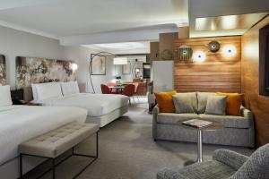 a hotel room with two beds and a couch at London Marriott Hotel Kensington in London