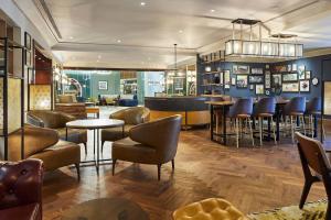 a bar with chairs and tables in a restaurant at London Marriott Hotel Kensington in London