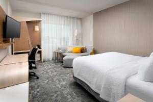 a hotel room with a bed and a desk and a chair at Courtyard Houston NW/290 Corridor in Houston