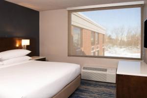 a hotel room with a bed and a large window at Delta Hotels by Marriott Detroit Metro Airport in Romulus