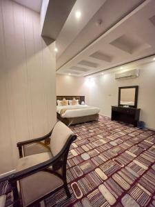 Cette chambre comprend deux lits, une chaise et un canapé. dans l'établissement فندق مرسى جيزان, à Jazan