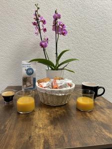 a table with a vase of flowers and two cups of orange juice at Au 15 - Charmant Studio hyper centre in Saint-Amand-Montrond