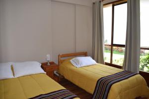 two beds in a room with a window at Casa Pablo in Cajamarca