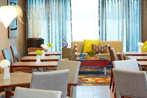 a restaurant with tables and chairs and a couch at Courtyard by Marriott Ithaca Airport/University in Ithaca