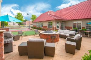 a patio with a fire pit and furniture and an umbrella at Residence Inn by Marriott Springdale in Springdale