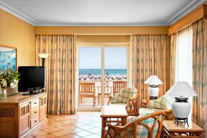 een woonkamer met een televisie en uitzicht op de oceaan bij Sheraton Soma Bay Resort in Hurghada
