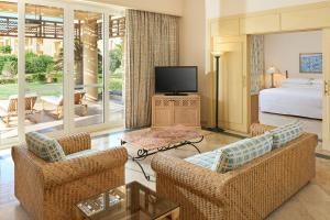 a living room with two chairs and a bed and a television at Sheraton Soma Bay Resort in Hurghada