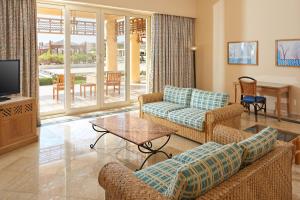 a living room with couches and a tv and a table at Sheraton Soma Bay Resort in Hurghada