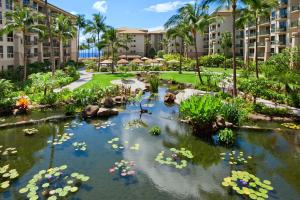 a garden with a pond with flowers and buildings at The Westin Ka'anapali Ocean Resort Villas North in Lahaina