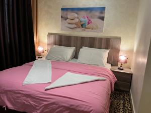 a bedroom with a pink bed with two lamps at Suzan Hotel Apartments in Amman