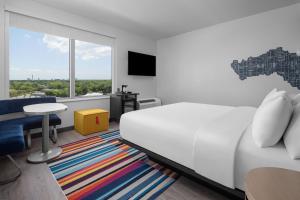 a bedroom with a white bed and a table and a window at Aloft Tampa Midtown in Tampa