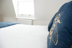 a bed with a blue pillow with gold embroidery on it at Margarets Buildings in Bath