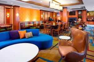 a lobby with a blue couch and chairs and a restaurant at Fairfield Inn & Suites by Marriott Cumberland in Cumberland