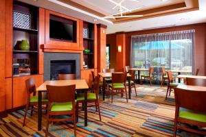 a restaurant with tables and chairs and a fireplace at Fairfield Inn & Suites by Marriott Cumberland in Cumberland