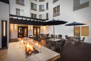 ein Restaurant mit Tischen und Sonnenschirmen und einem Kamin in der Unterkunft Courtyard by Marriott Anaheim Resort/Convention Center in Anaheim