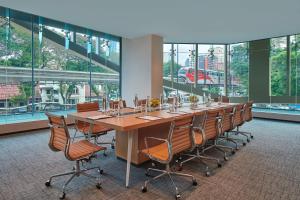 Fairfield by Marriott Chow Kit Kuala Lumpur في كوالالمبور: طاولة وكراسي طويلة في غرفة بها نوافذ