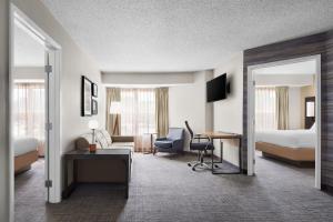 ein Hotelzimmer mit einem Schreibtisch und einem Schlafzimmer in der Unterkunft Residence Inn Indianapolis Northwest in Indianapolis