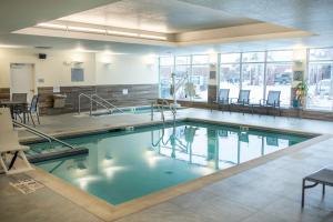 a swimming pool with chairs and tables in a building at Fairfield Inn & Suites Winona in Winona