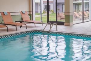 a swimming pool at a hotel with two chairs at Courtyard by Marriott Detroit Warren in Warren