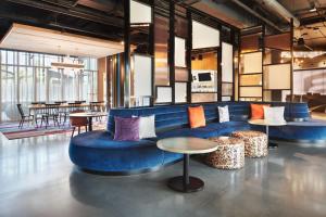 サンディスプリングスにあるAloft Atlanta Perimeter Centerの青いソファとテーブルが備わるロビー
