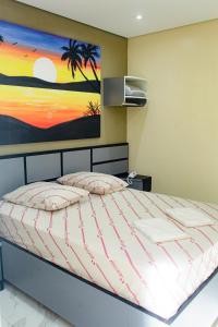 a bedroom with a bed with a painting on the wall at Hotel Tenda Obsession in Sao Paulo