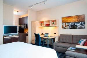 a hotel room with a bed and a desk and a couch at TownePlace Suites Des Moines Urbandale in Johnston