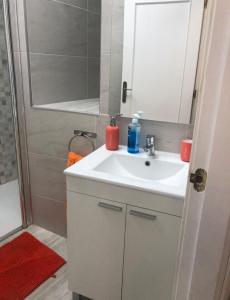 La salle de bains est pourvue d'un lavabo blanc et d'une douche. dans l'établissement Milan Soria Luxury House, à Benidorm