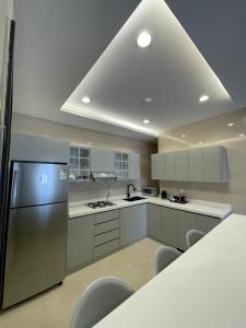 una cocina con nevera de acero inoxidable y armarios blancos en MJ Private APARTMENT en Riad