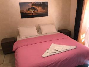 una camera con un letto rosa e un accappatoio. di Suzan Hotel Apartments ad Amman