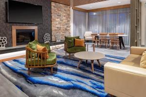 a lobby with chairs and a table and a fireplace at Fairfield Inn & Suites by Marriott Queensbury Glens Falls/Lake George in Queensbury