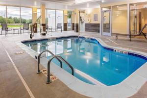 a swimming pool in a hotel with tables and chairs at Fairfield Inn & Suites by Marriott Queensbury Glens Falls/Lake George in Queensbury