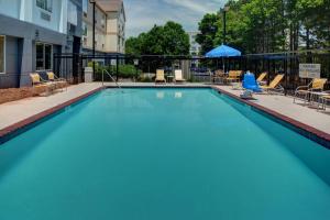 una gran piscina azul con sillas y sombrilla en Fairfield Inn & Suites by Marriott Atlanta Alpharetta, en Alpharetta