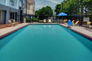 uma grande piscina azul com cadeiras e um guarda-sol em Fairfield Inn & Suites by Marriott Atlanta Alpharetta em Alpharetta