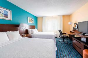 ein Hotelzimmer mit 2 Betten, einem Schreibtisch und einem TV in der Unterkunft Fairfield Inn & Suites Mansfield Ontario in Mansfield
