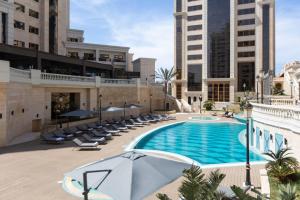 una piscina all'aperto con sedie e ombrellone di Residence Inn by Marriott Algiers Bab Ezzouar a Alger