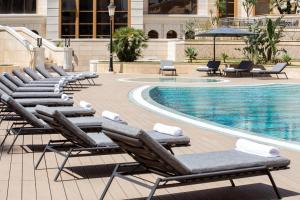 a row of chaise lounge chairs next to a swimming pool at Residence Inn by Marriott Algiers Bab Ezzouar in Alger