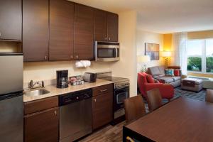 uma cozinha com armários de madeira e uma sala de estar em TownePlace Suites by Marriott Jacksonville em Jacksonville