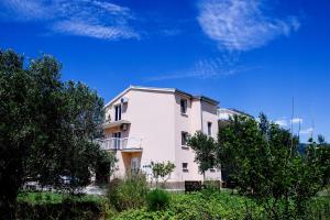 a white building with trees in front of it at Apartman Sunny Vacay in Kaštela