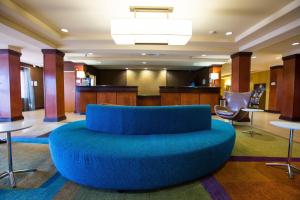a large blue couch in a lobby with tables and chairs at Fairfield Inn & Suites Toledo North in Toledo