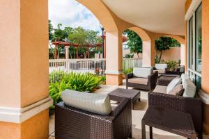 un patio al aire libre con mesas y sillas de mimbre en Courtyard Fort Myers at I-75 and Gulf Coast Town Center en Estero