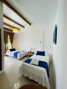 a bedroom with two beds with blue and white sheets at Fernandina Hotel & Spa in Puerto Ayora