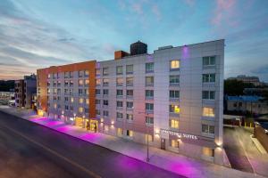 a white building with purple lights on a city street at SpringHill Suites by Marriott New York JFK Airport Jamaica in Queens