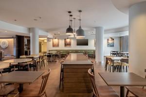 Fairfield Inn & Suites by Marriott New Braunfels في نيو بروانفيلز: غرفة طعام مع طاولات وكراسي وتلفزيون