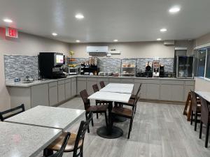 a restaurant with tables and chairs and a kitchen at Best Western El Rancho Palacio in Roswell