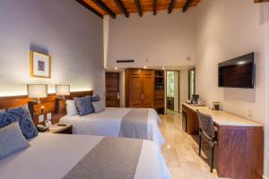 a hotel room with two beds and a television at Buenaventura Grand Hotel & Great Moments - All Inclusive in Puerto Vallarta